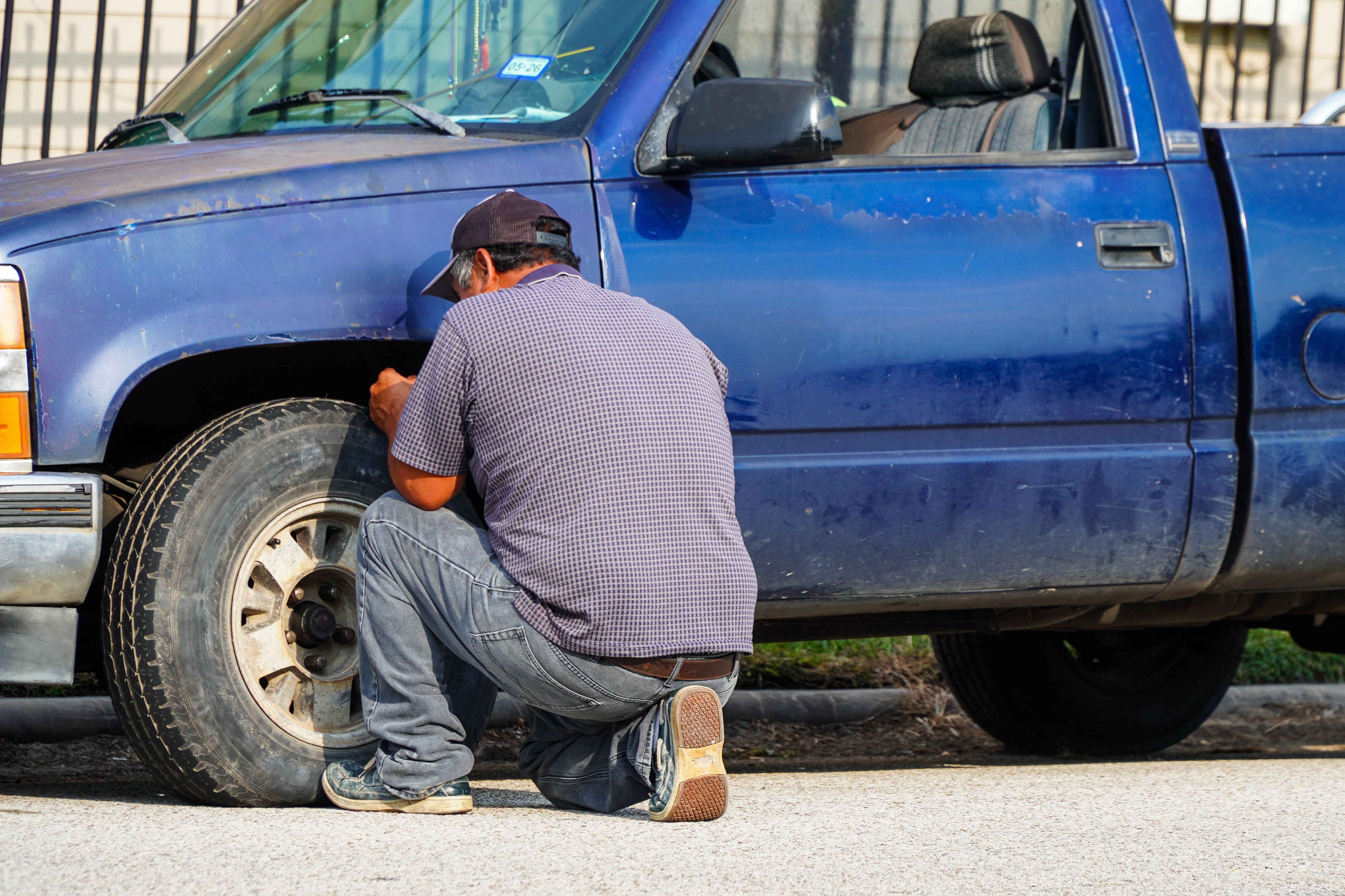 Man repairing a flat tire on a truck beside the road